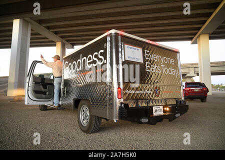 Ehrenamtlich bei Mobile Brotes and Fishes, einem in Austin ansässigen Ministerium, das Mahlzeiten an Obdachlose verteilt, verteilt Mahlzeiten in einem Obdachlosenlager unter einer Autobahnüberführung in Austin. Stockfoto