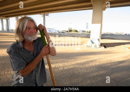 Nachdem Texas reg. Greg Abbott verkündete ein Durchgreifen auf zeltdörfer in öffentlichen Räumen, ein Mann reinigt die Fläche unter einem Austin, Texas, Autobahnbrücke, wo er und andere ein temporäres Lager für Obdachlose eingerichtet haben. Stockfoto