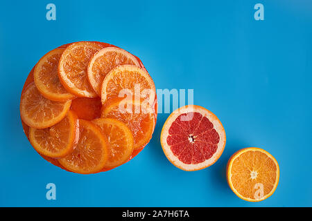 Ansicht von oben in einem kalten Hausgemachte orange Kuchen mit kandierten Orangen auf der Oberfläche, Orangenmarmelade, orange Mousse und Spekulatius auf blauem Hintergrund. Stockfoto