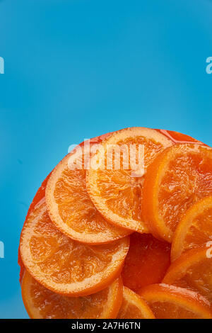 Ansicht von oben und in der Nähe eines kalten Hausgemachte orange Kuchen mit kandierten Orangen auf der Oberfläche, Orange Marmelade, orange Mousse und almond Cookie auf einem blauen backgrou Stockfoto