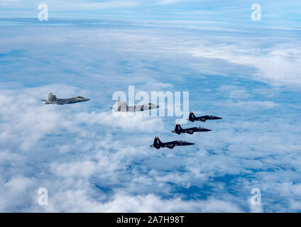 F-22 Raptors und T-38 Talons vom 1 Fighter Wing fliegen in Formation auf den Atlantischen Ozean während der Ausbildung an der Küste von Virginia, Okt. 30, 2019. Die 1 Fighter Wing ist die Heimat der 94th Fighter Squadron, 27 Fighter Squadron und der 71St Fighter Training Squadron bei Joint Base Langley-Eustis (USA, Virginia. Air Force Foto von Tech Sgt. Carlin Leslie) (freigegeben) Stockfoto