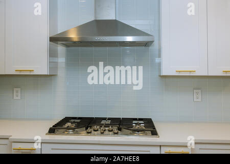 Küche mit weißen Schränke mit Ablageflächen aus Marmor mit Stein Edelstahl Haube Küche Interieur mit neuen Backofen gekoppelt Stockfoto