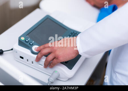 Nahaufnahme Foto auf einem EKG-Gerät, während ein alter Mann sein Herz überprüft. Stockfoto