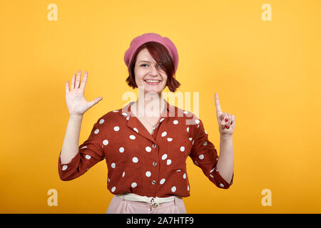 Junges Mädchen zeigt und nach oben mit den Fingern während lächelte zuversichtlich, glücklich Stockfoto