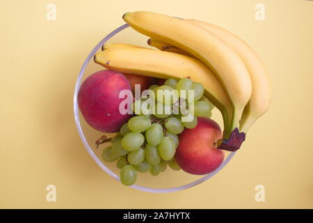 Direkt oberhalb des bunten Früchte in eine Schüssel gegen die gelben Hintergrund Stockfoto