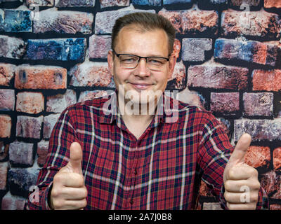 Ein Mann mit Brille zeigt eine gute Geste. Symbole und Gesten. Auf "Ok". Stockfoto