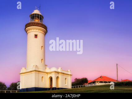 Weißer Stein Leuchtturm auf Norah Head von Australian Pacific Central Coast bei Sonnenaufgang gegen blau und rosa Himmel mit Beleuchtung Reflektor spiegeln Drehen einer Stockfoto