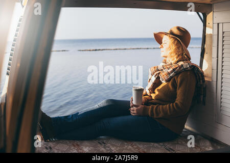Junge blonde kaukasische Frau entspannen in Ihrem Wohnmobil bei Sonnenuntergang Stockfoto