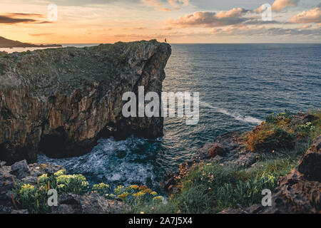 Landschaft mit Silhouette eines Mannes stehen am Rand der Klippe an der Küste im Norden von Spanien, Asturien, Europa bei Sonnenuntergang im Sommer Stockfoto
