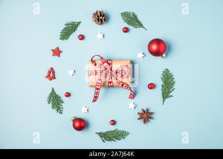 Weihnachten Komposition. Weihnachten Kranz aus Tanne Baum verzweigt, Dekorationen, Beeren mit Geschenkbox auf blauem Hintergrund. Weihnachten, Winter, neues Jahr Stockfoto