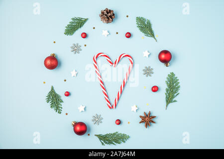 Weihnachten Komposition. Weihnachten Kranz aus Tanne Baum verzweigt, Dekorationen, Beeren mit Candy Herz auf blauem Hintergrund. Weihnachten, Winter, neue Ihr Stockfoto