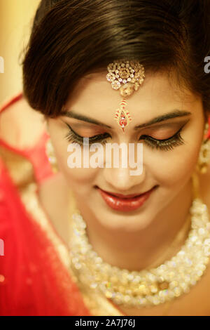 Atemberaubende indische Braut in der hinduistischen Rot traditionelle Hochzeit Kleidung sari mit Gold Schmuck bestickt und ein Schleier lächelt zart mit zusätzlichen Kopie spa Stockfoto