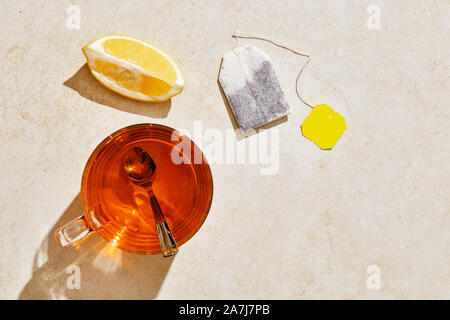 Tasse Tee, Zitrone und Teebeutel auf Marmor tisch mit harten Sommer Sonnenlicht. Ansicht von oben mit Kopie Raum Stockfoto