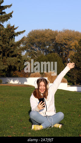 Happy Jugendmädchen hört Musik von Ihrem Smartphone in Park Stockfoto