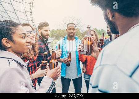 Vielfältige Gruppe von Freunden, genießen Sie ein Bier im Park Stockfoto
