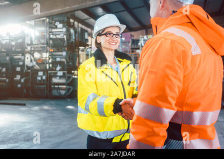 Mitarbeiter und Kunden im Lager tun Handshake Stockfoto