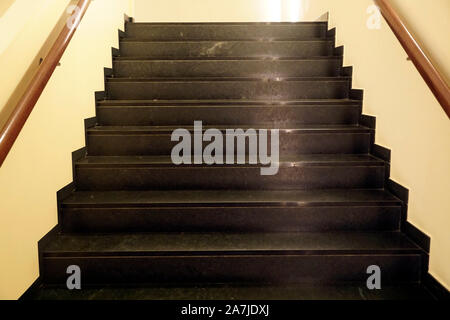 Dunkle braune Treppe mit Reflexion der Gelben Strahlen von künstlichem Licht Stockfoto