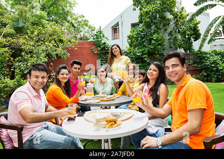 Gruppe - von glücklichen Indischen große Familien Mitglieder essen Frühstück gemeinsam im Innenhof in der Nähe Ihres Hauses Stockfoto