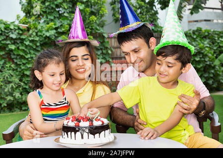 Glückliche junge Familie Kinder Geburtstag feiern Eltern und zwei Kinder gemeinsam feiern im Innenhof in der Nähe Ihres Hauses Stockfoto