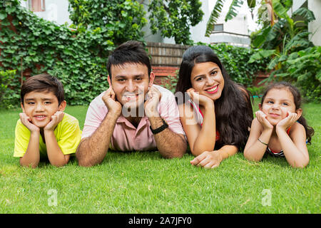 Glückliche Familie Eltern und Two-Children ist entspannt Liegend auf Gras, die zusammen im Garten Ihres Hauses Stockfoto