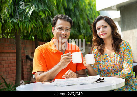 Happy indischen Ehepaar sitzt am Tisch und trinken Kaffee oder Tee im Haus Hof in Morgen Stockfoto