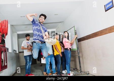 Erfolgreiche Junge männliche Studenten Springen feiern ihr Ergebnis mit Studenten At-Campus Stockfoto