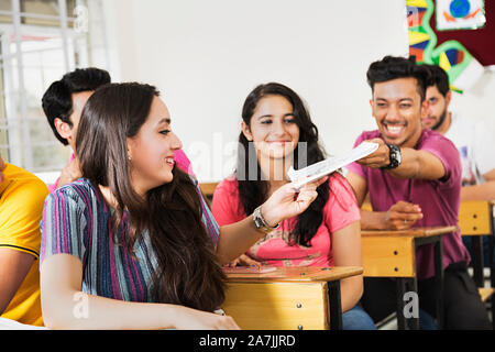 College Campus Studenten sitzen On-Table Junge geben Buch Mädchen At-Classroom Stockfoto