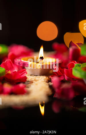 Close-up Burning Diya Oil-Lamp mit Rosenblättern während Diwali Fest Feier Niemand Stockfoto