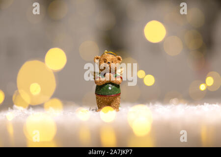 Dekorative Figuren aus einem Thema Weihnachten. Figurine eines süßen Bär mit Angel Wings. Festliches Dekor, warme Bokeh leuchtet. Stockfoto