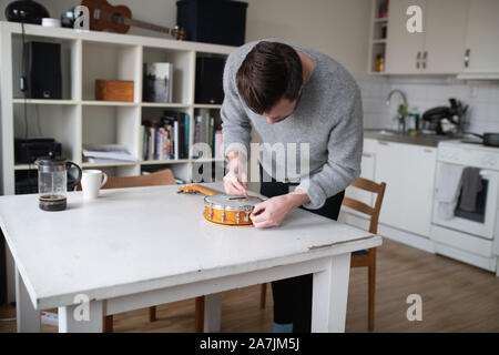 Mann Ersetzen von Strings am Banjo ukulele Stockfoto