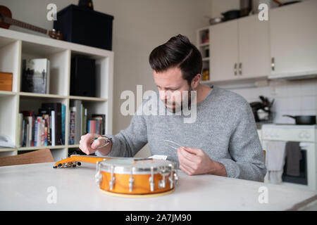 Mann Ersetzen von Strings am Banjo ukulele Stockfoto