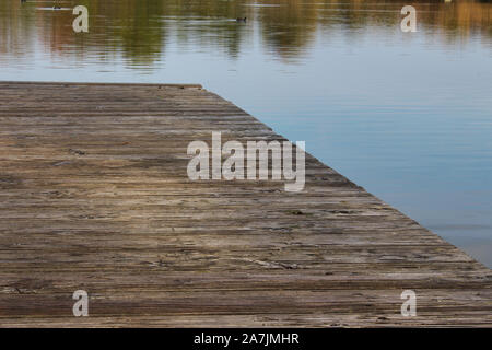 Alte hölzerne Promenade am See mit reflektierenden Bäume im Wasser Stockfoto