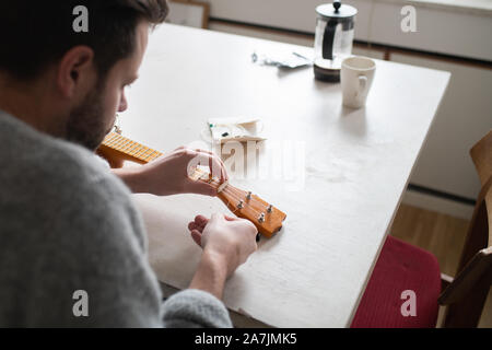 Mann Ersetzen von Strings am Banjo ukulele Stockfoto