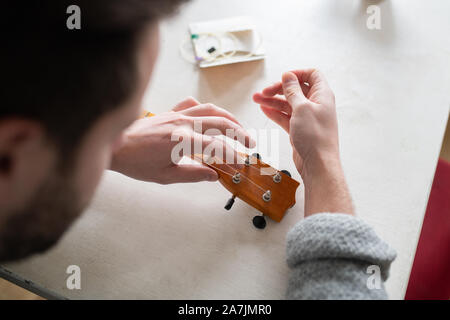 Mann Ersetzen von Strings am Banjo ukulele Stockfoto