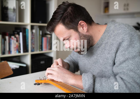 Mann Ersetzen von Strings am Banjo ukulele Stockfoto