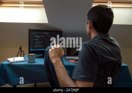 Junger Mann raucht einen joint und Getränke Kaffee zu Hause, während der Arbeit mit Computern. Konzept der das Rauchen von Marihuana und Nutzung der Technologie. Stockfoto