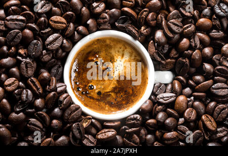 Weiße Tasse mit Kaffee und Kaffeebohnen umgeben. Konzeptionelle Bild. Stockfoto