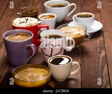 Viel Kaffee in verschiedenen Cups auf alten Holztisch Stockfoto