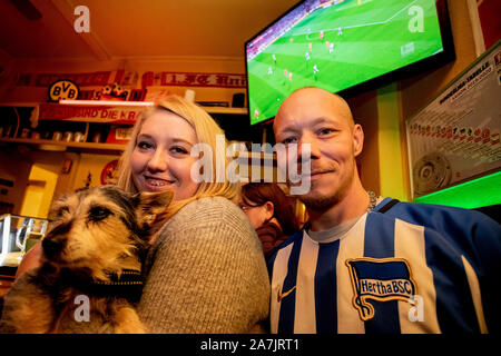 Berlin, Deutschland. 02 Nov, 2019. Marcus Welk, Hertha fan, steht neben Solveig Freiberg, 'Fan-Anhang' und fördern Hund Tapsi während des Derby zwischen Hertha BSC und dem 1. FC Union Berlin in der kiezkneipe Schwarze Hexe im Prenzlauer Berg. (Dpa: 'Störer in der Minderheit - Fans sind glücklich über die erste Stadt Derby vom 03.11.2019) Quelle: Christoph Soeder/dpa/Alamy leben Nachrichten Stockfoto