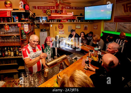 Berlin, Deutschland. 02 Nov, 2019. Frank Schaffors (l), bar Inhaber und Union Fan, und seine Verlobte Sylvia Winkler (M), Werder Bremen fan, befinden sich hinter der Bar im Derby zwischen Hertha BSC und dem 1. FC Union Berlin in der kiezkneipe Schwarze Hexe im Prenzlauer Berg. (Dpa: 'Störer in der Minderheit - Fans sind glücklich über die erste Stadt Derby vom 03.11.2019) Quelle: Christoph Soeder/dpa/Alamy leben Nachrichten Stockfoto