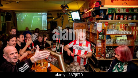 Berlin, Deutschland. 02 Nov, 2019. Frank Schaffors (M), bar Inhaber und Union Fan, und seine Verlobte Sylvia Winkler (r), Werder Bremen fan, befinden sich hinter der Bar im Derby zwischen Hertha BSC und dem 1. FC Union Berlin in der kiezkneipe Schwarze Hexe im Prenzlauer Berg. (Dpa: 'Störer in der Minderheit - Fans sind glücklich über die erste Stadt Derby vom 03.11.2019) Quelle: Christoph Soeder/dpa/Alamy leben Nachrichten Stockfoto