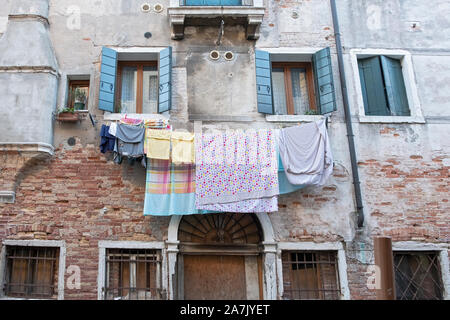 Wäsche aufhängen auf der Seite von einem Gebäude aus dem 16. Jahrhundert in einer Seitenstraße zum Trocknen an einem Kanal in der Nähe von Campo San Provolo Castello in Venedig, Italien. Stockfoto