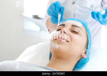 Frau Doktor Kosmetikerin gilt eine Maske auf das Gesicht eines Patienten für die Hautpflege. Kosmetische Verfahren zur Hautverjüngung und Ernährung. Stockfoto