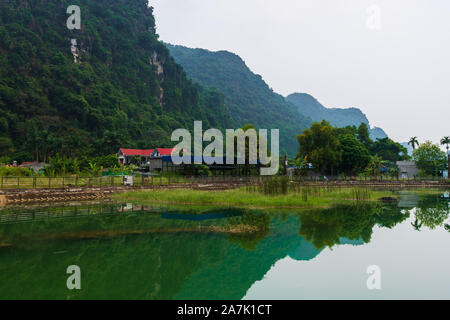 Berge spiegeln sich in eine Glut grüner See auf der versteckten Insel Cat Ba, die regelmäßig mit dem Boot Touren rund um Ha Long Bay besucht wird Stockfoto