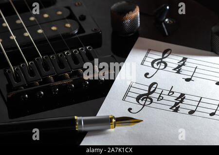 Musik Hinweis und Vintage pen auf Schwarz E-Gitarre in der Dunkelheit. Konzept der Rockmusik kreativ. Stockfoto