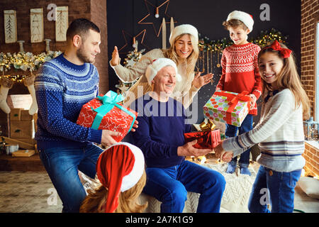 Eine große Familie in einem Zimmer gibt Geschenke zu Weihnachten. Stockfoto