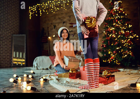 Mädchen Geschenk versteckt hinter zurück, während in Weihnachten Stockfoto