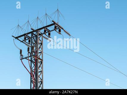 Turm mit drei Stromleitungen und Schutzelemente. Revolver mit Starkstrom Kabel auf eine Quelle des blauen Himmel ohne Wolken Stockfoto