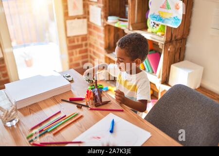 Schöne afrikanische amerikanische Kleinkind spielen mit Dinosaurier Spielzeug auf dem Schreibtisch im Kindergarten Stockfoto