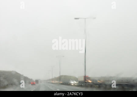 Autos auf einer Autobahn in Großbritannien gesehen durch einen regen bedeckt Frontscheibe Stockfoto